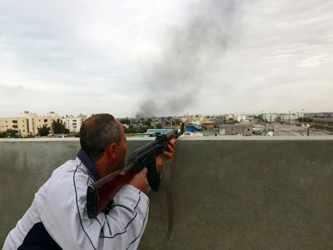 Una espesa columna de humo negro se elevaba sobre el complejo de Gadafi, situado cerca del hotel...