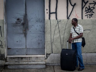 Un hombre haitiano, con su maleta a la entrada de un refugio para inmigrantes en la ciudad...