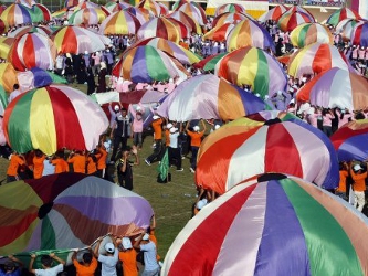 Unos niños se entretienen con unos paracaídas de colores durante los 'Juegos de...
