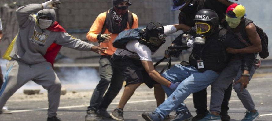 Manifestantes ayudan a un periodista herido en una pierna mientras cubría los...