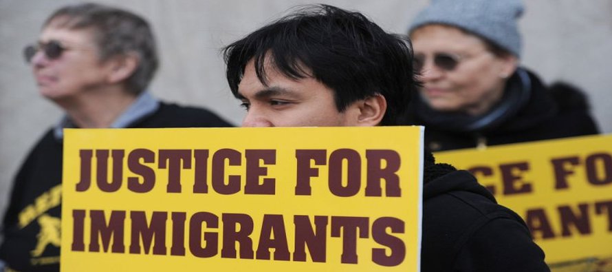 Chris Magno sostiene un letrero que dice Justicia para los inmigrantes, durante una protesta...