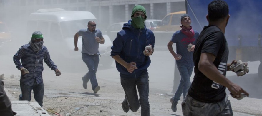 Columnas de humo negro se alzaban de neumáticos encendidos y los palestinos arrojaban...