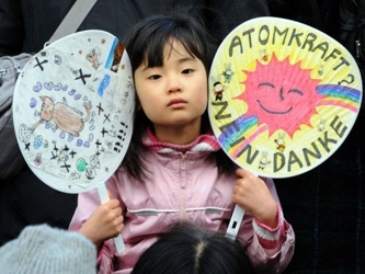 Una niña muestra unos abanicos dibujados durante una protesta contra la energía...