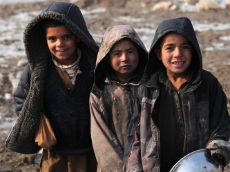 Unos niños afganos desplazados dentro de su país, posan ante unos refugios a las...