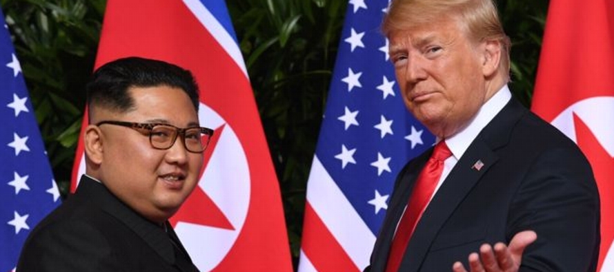 Kim y Trump se estrecharon las manos y sonrieron brevemente frente a una hilera de banderas de...
