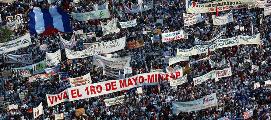 Pancartas con lemas de apoyo a la revolución, en contra de las sanciones, coloridas banderas...