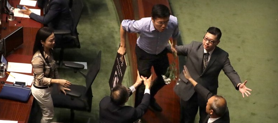 Legisladores prodemocracia gritaron y ondearon carteles que mostraban a Lam con las manos manchadas...