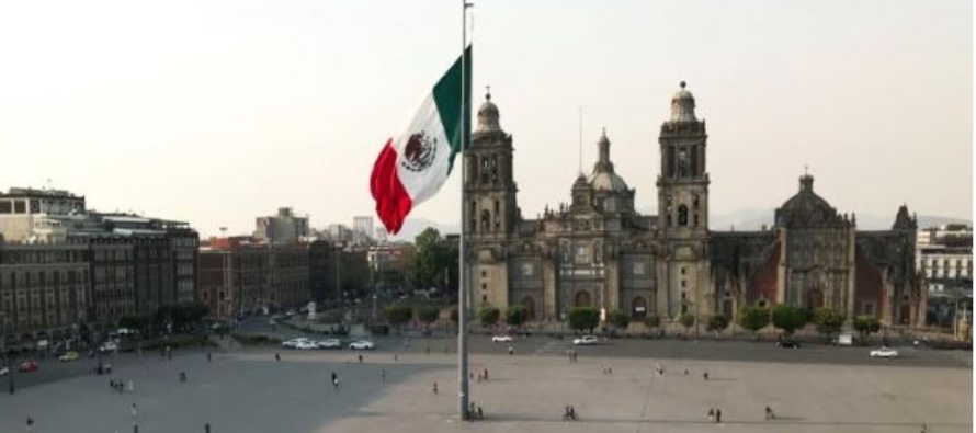 Imagen de archivo. Personas caminan cerca de la bandera nacional en una Plaza del Zócalo...