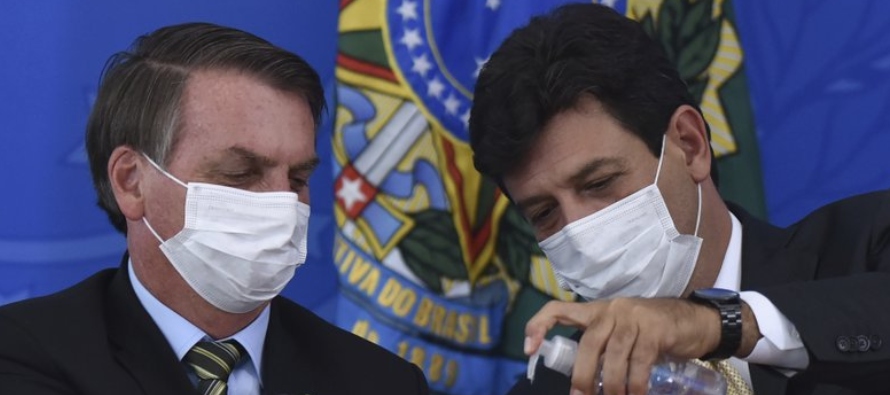 El ministro de salud de Brasil Luiz Henrique Mandetta, derecha, aplica desinfectante en las manos...