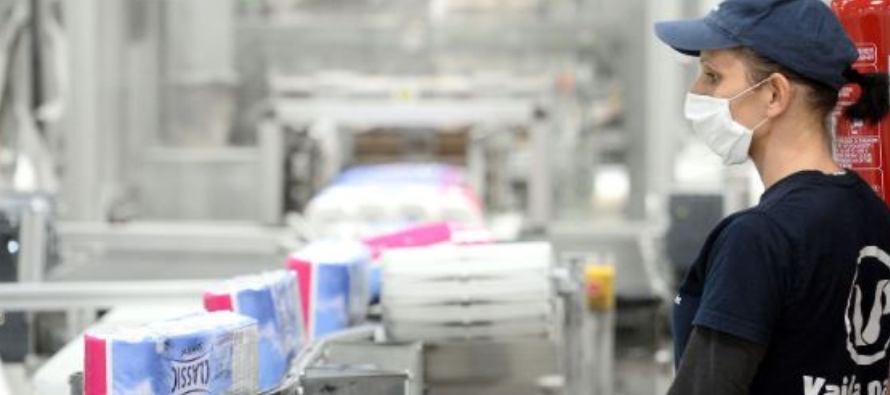 Una trabajadora supervisa una línea de producción de papel higiénico en una...