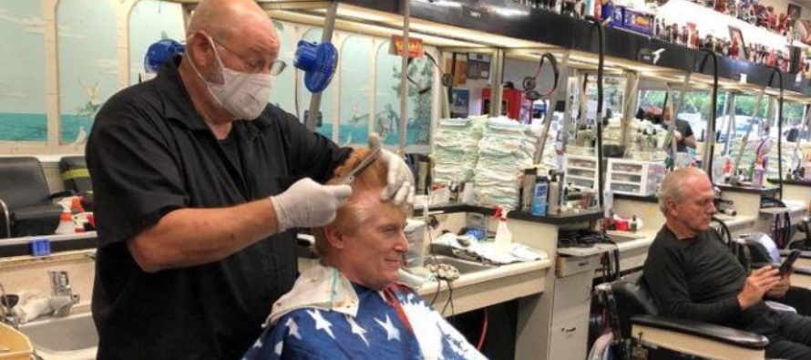 El barbero Tommy Thomas, de 69 años, que lleva 50 años en el oficio, le corta el pelo...