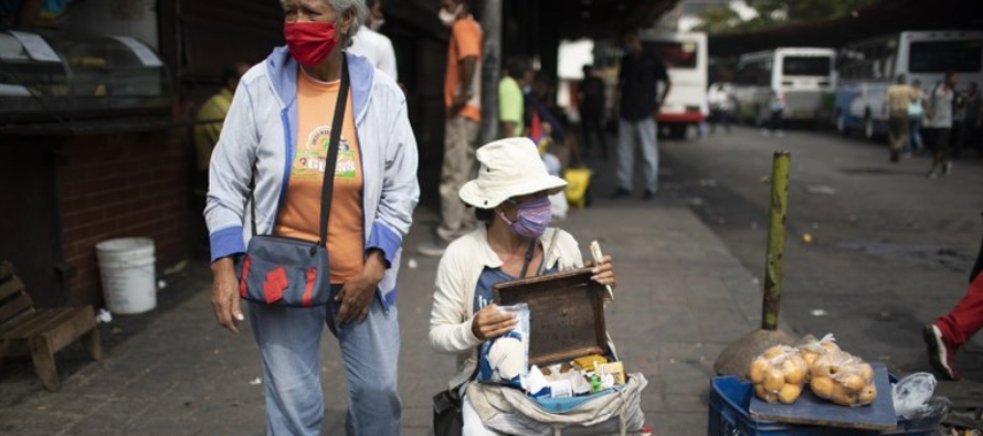 Vendedores callejeros usan mascarillas para protegerse del nuevo coronavirus mientras esperan...