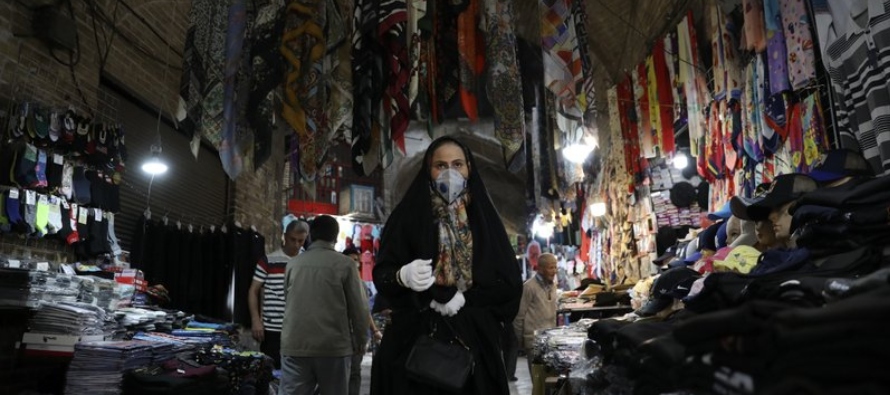 Una mujer con mascarilla y guantes para protegerse del coronavirus camina en el bazar tradicional...