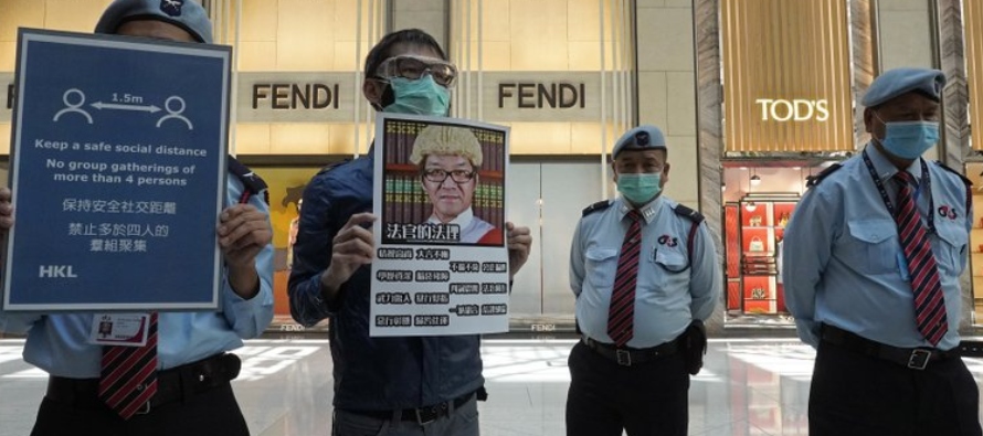 Un manifestante con una máscara protectora alza una pancarta que critica a un juez que...