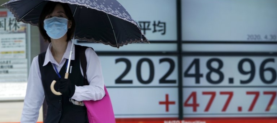 Una mujer frente a una cartelera financiera en Tokio el 30 de abril del 2020. (AP Photo/Eugene...