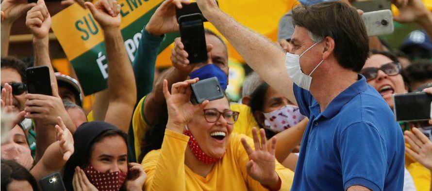 Con una mascarilla, el presidente de Brasil, Jair Bolsonaro, se fotografió con niños...