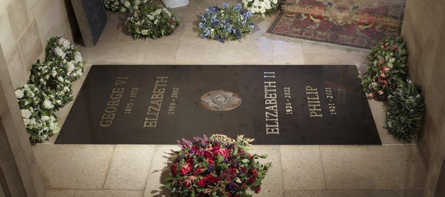 La nueva lápida, rodeada de ofrendas florales y ramos de flores, tiene inscrito el nombre de...
